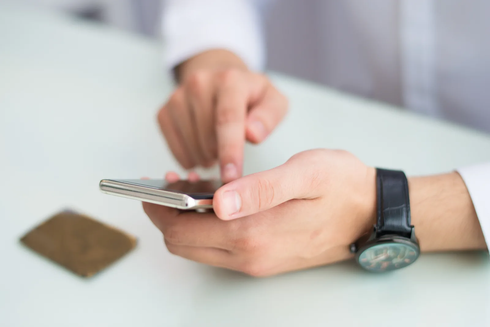 Persona consulta su teléfono junto a un reloj de pulsera